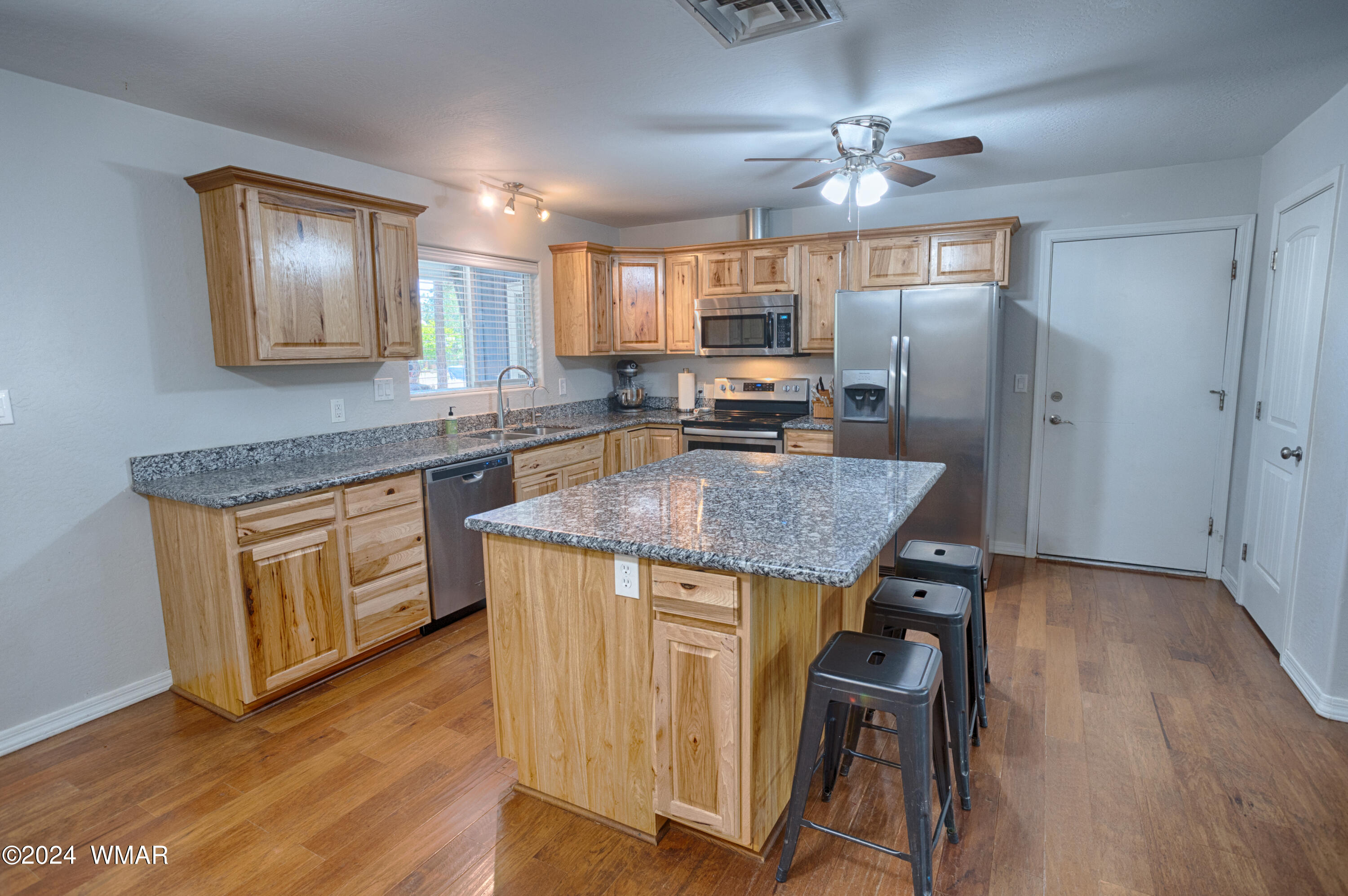 625 East Nora Place Pinetop, AZ 85935 - Photo 19 of 35 a kitchen with kitchen island granite countertop wooden floors and stainless steel appliances