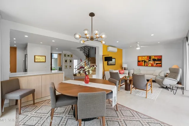 a view of a dining room and livingroom with furniture wooden floor a rug a painting and a chandelier