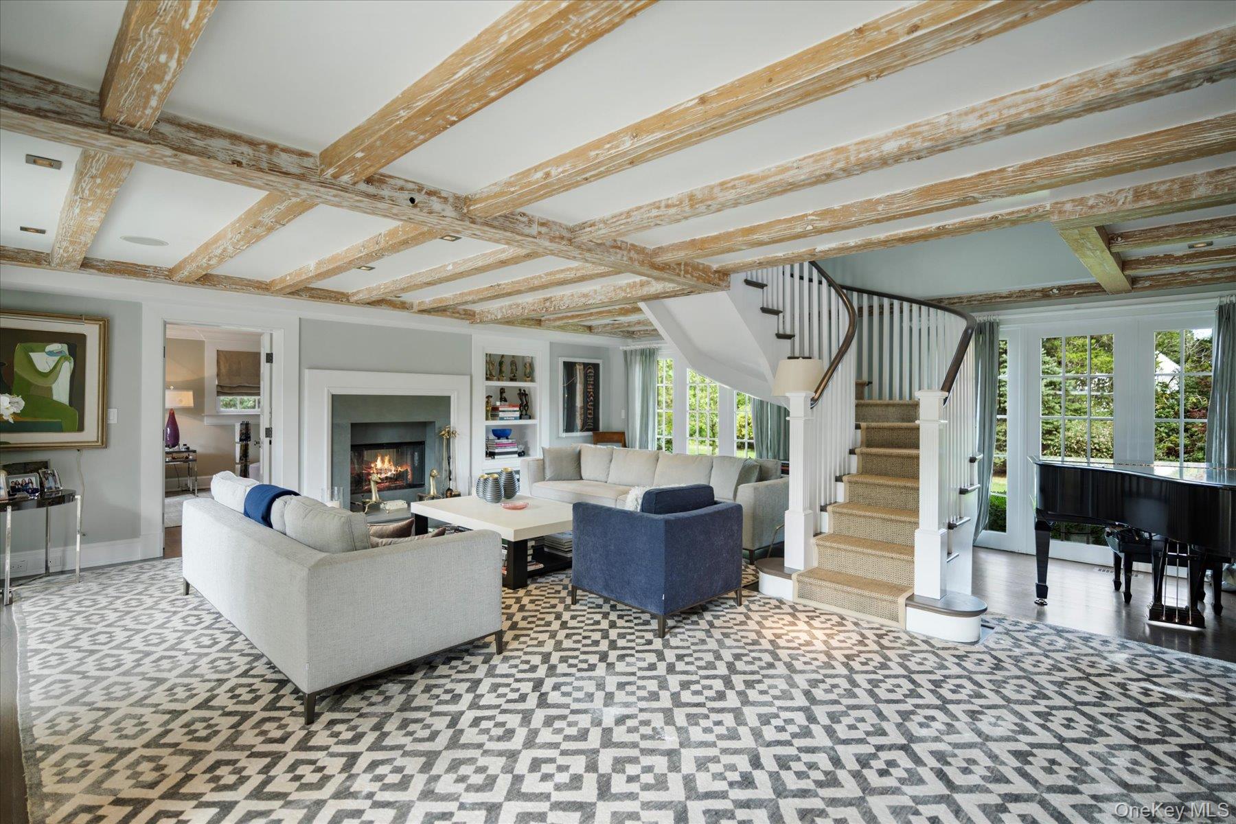 231 Flying Point Road Southampton, NY 11968 - Photo 9 of 34 Living room featuring beamed ceiling, a lit fireplace, and stairway