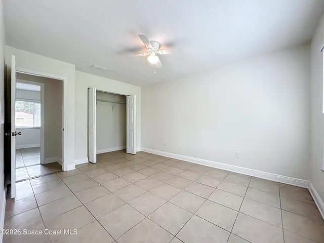 a view of an empty room with closet and a mirror