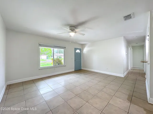 an empty room with windows and fan
