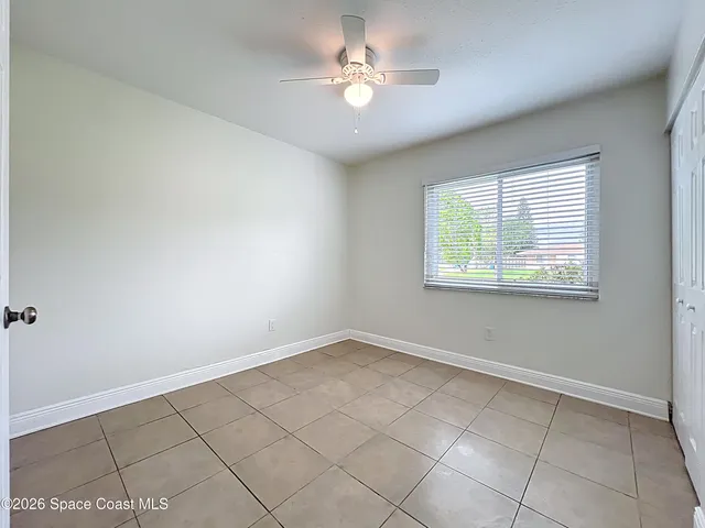 an empty room with windows and ceiling fan