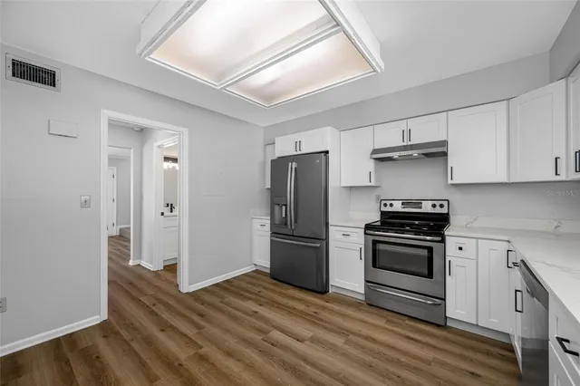 a kitchen with a refrigerator stove and wooden floor