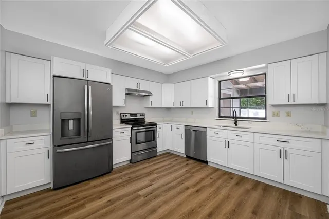 a kitchen with granite countertop a refrigerator stove and sink