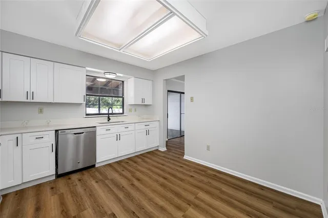 a kitchen with white cabinets and window
