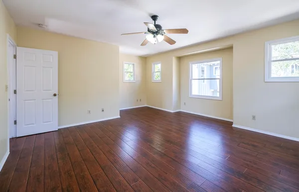 a view of an empty room with wooden floor and a window