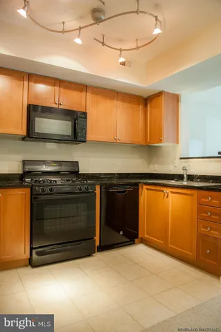 a kitchen with stainless steel appliances granite countertop a refrigerator a stove and a sink with wooden floor