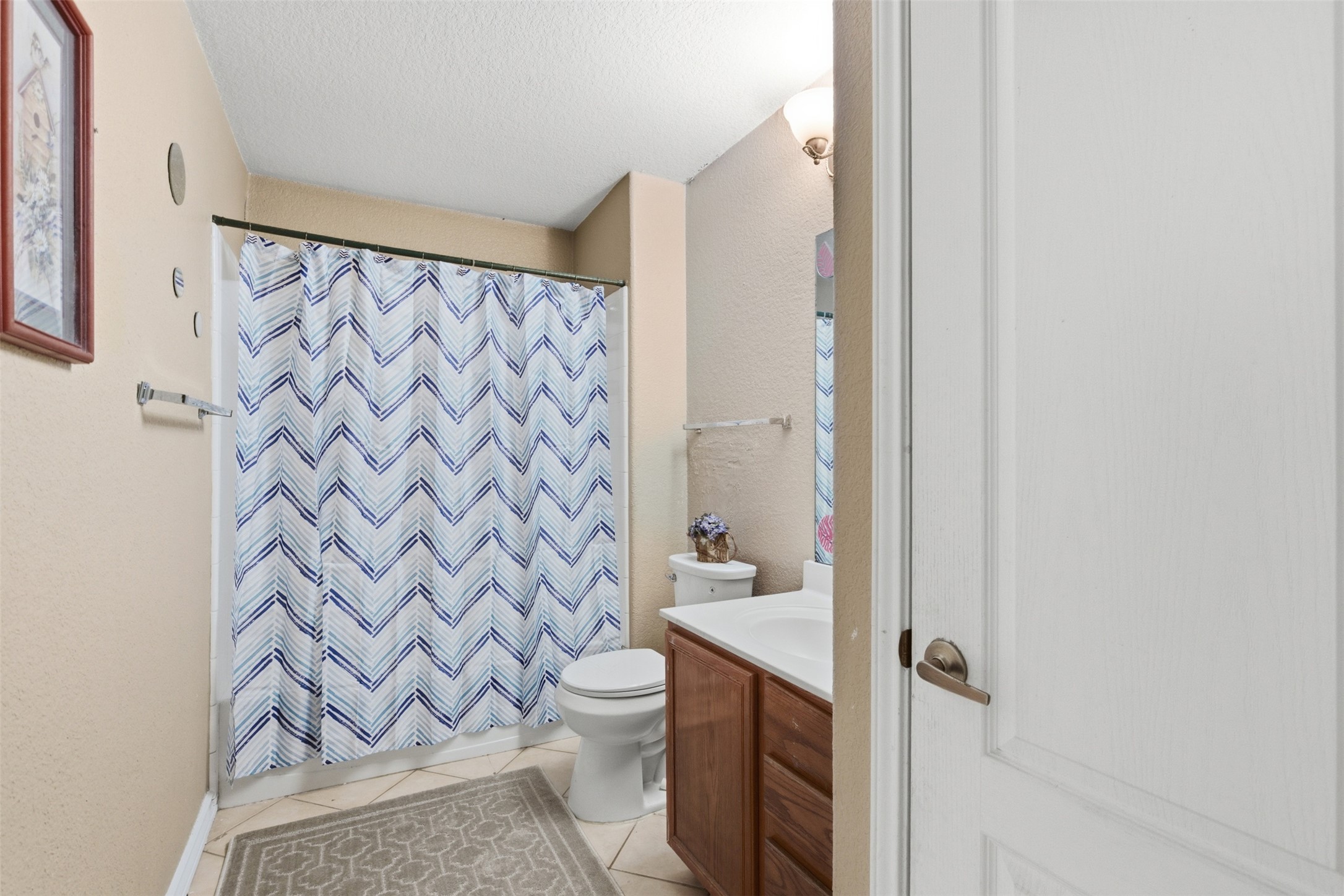 5701 Malarkey Road Del Valle, TX 78617 - Photo 14 of 27 Bathroom with vanity, light tile patterned floors, a textured ceiling, a textured wall, and shower / bath combo