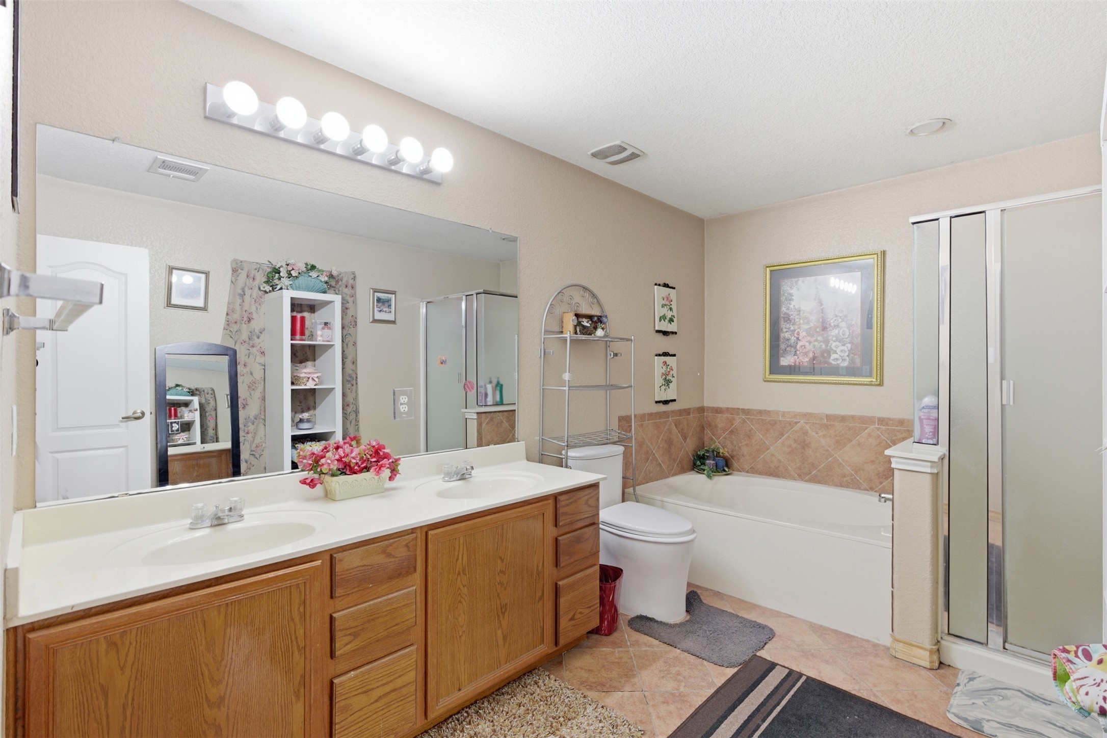 5701 Malarkey Road Del Valle, TX 78617 - Photo 17 of 27 Bathroom with double vanity, a stall shower, a garden tub, and light tile patterned floors