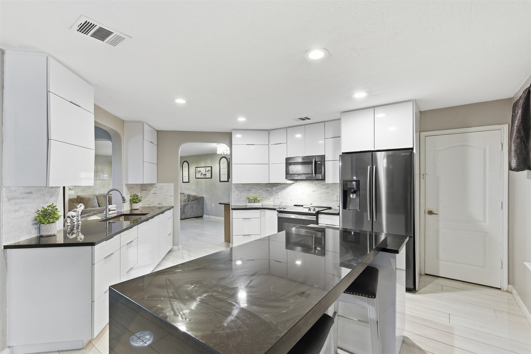 5701 Malarkey Road Del Valle, TX 78617 - Photo 9 of 27 Kitchen featuring modern cabinets, arched walkways, white cabinets, stainless steel appliances, and dark stone counters