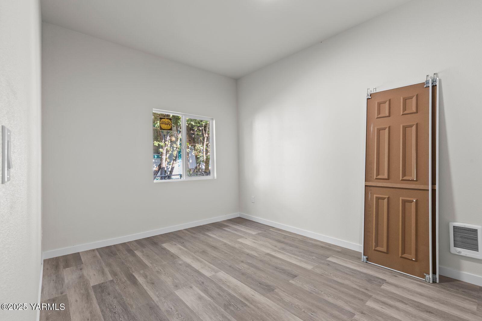 711 North 3rd Street Yakima, WA 98901 - Photo 8 of 21 an empty room with wooden floor closet and windows