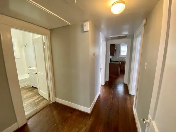 a view of a hallway with wooden floor and a bathroom