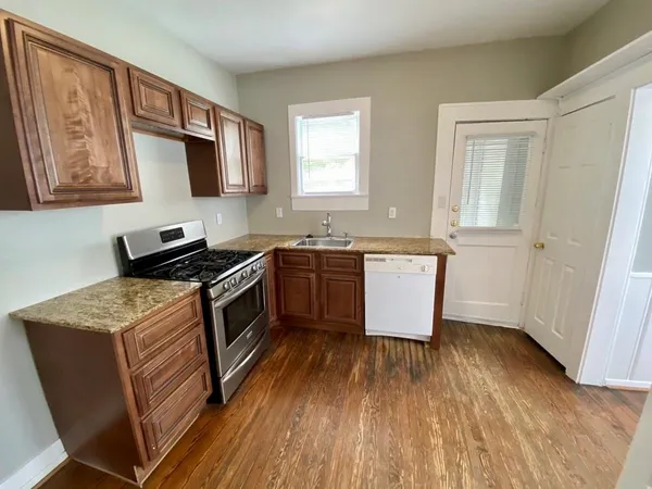 a kitchen with a sink stove top oven and wooden floor