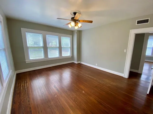 a view of an empty room with wooden floor and a window