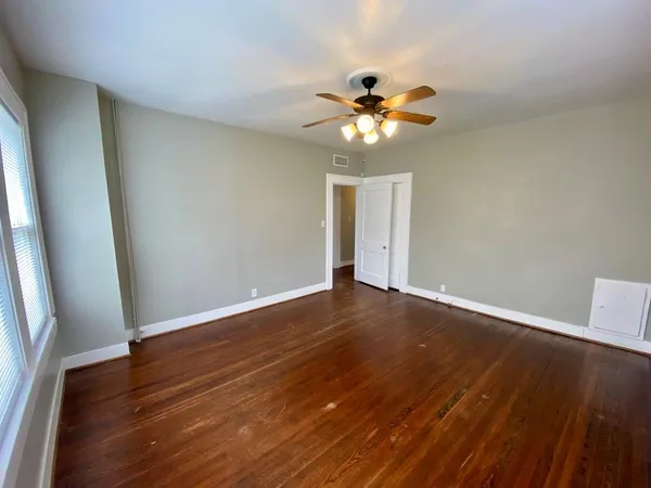 a view of an empty room with wooden floor and a window