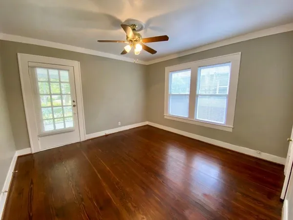 a view of an empty room with wooden floor and a window