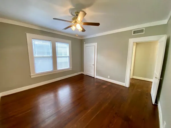 a view of an empty room with wooden floor and a window