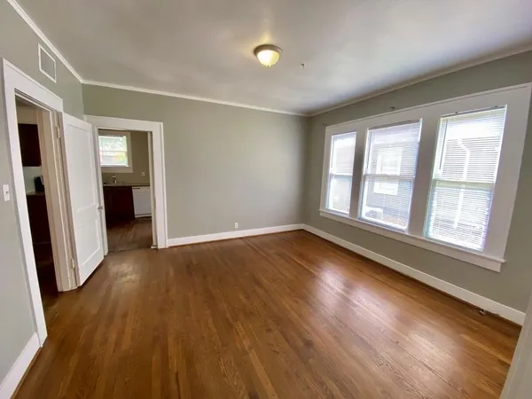 an empty room with wooden floor and windows