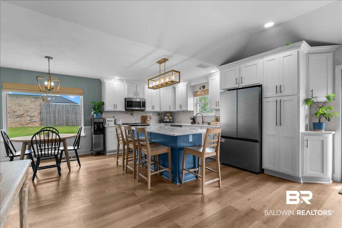 8952 Sherman Road Foley, AL 36535 - Photo 14 of 41 Kitchen featuring a blue island with a white countertop, white shaker cabinetry, stainless steel appliances, and wood-finish flooring