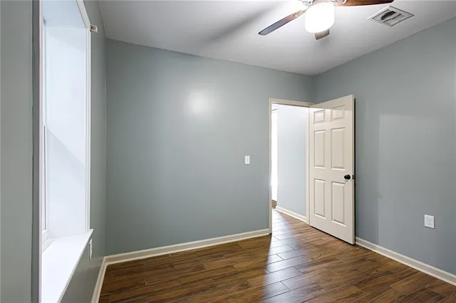 an empty room with wooden floor and windows