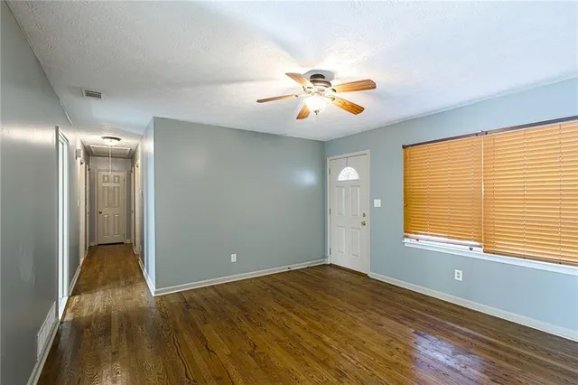 a view of empty room with wooden floor and fan