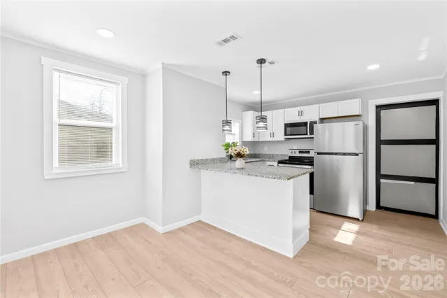 a kitchen with a refrigerator wooden floor and white cabinets