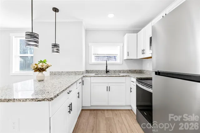 a kitchen with stainless steel appliances granite countertop a sink a stove and a wooden floor