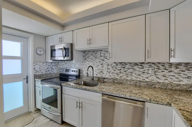 a kitchen with granite countertop a sink a stove and cabinets