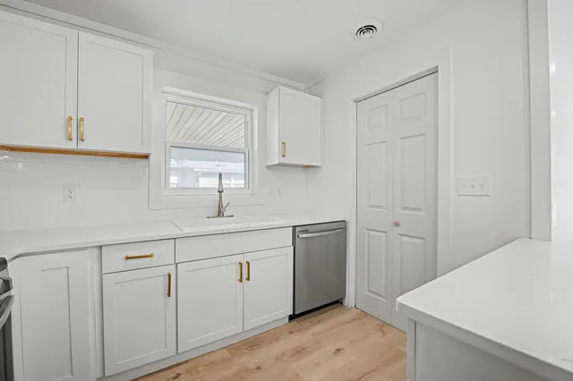 a view of a kitchen from the hallway with a window and wooden floor