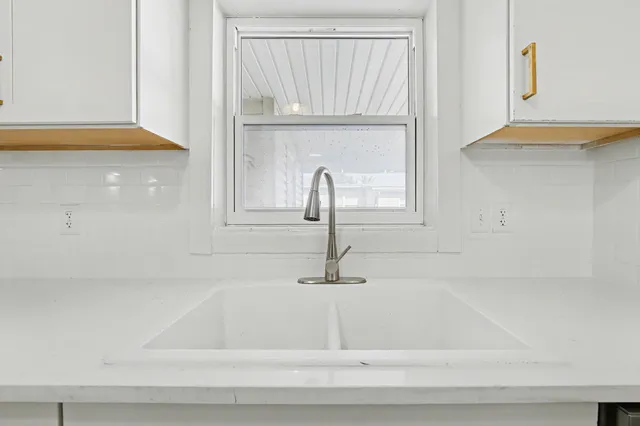 an empty room with wooden floor a ceiling fan and windows
