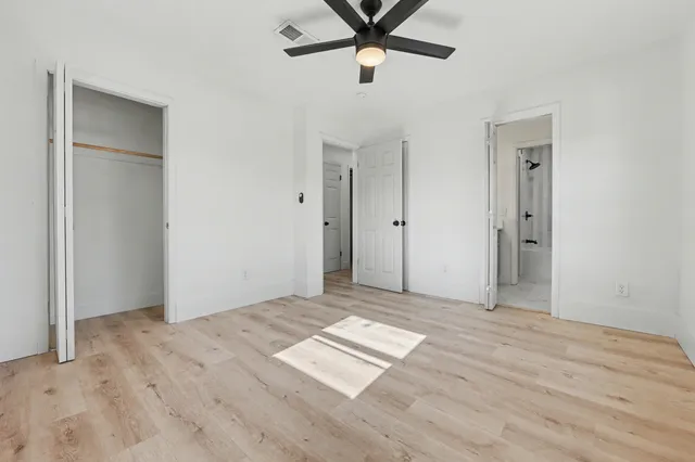 an empty room with wooden floor and ceiling fan