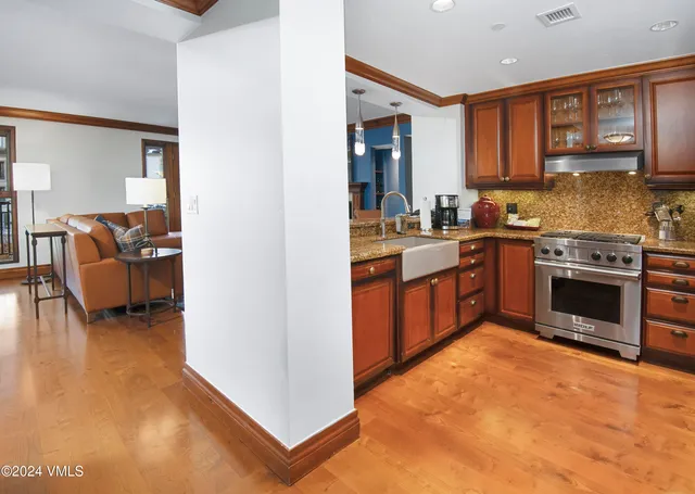 a kitchen with stainless steel appliances granite countertop a stove top oven a sink dishwasher and cabinets with wooden floor