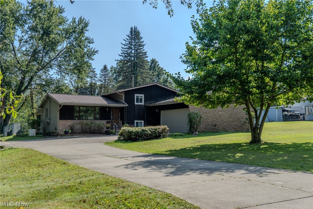 2848 Pressler Road Uniontown, OH 44685 - Photo 2 of 37 Multi-level exterior with brick and dark siding, extensive driveway, attached garage, and mature trees