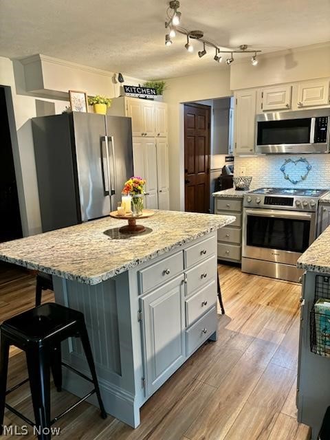 104 Marshall Road Marietta, OH 45750 - Photo 18 of 37 Kitchen featuring a kitchen island, appliances with stainless steel finishes, tasteful backsplash, and a kitchen breakfast bar