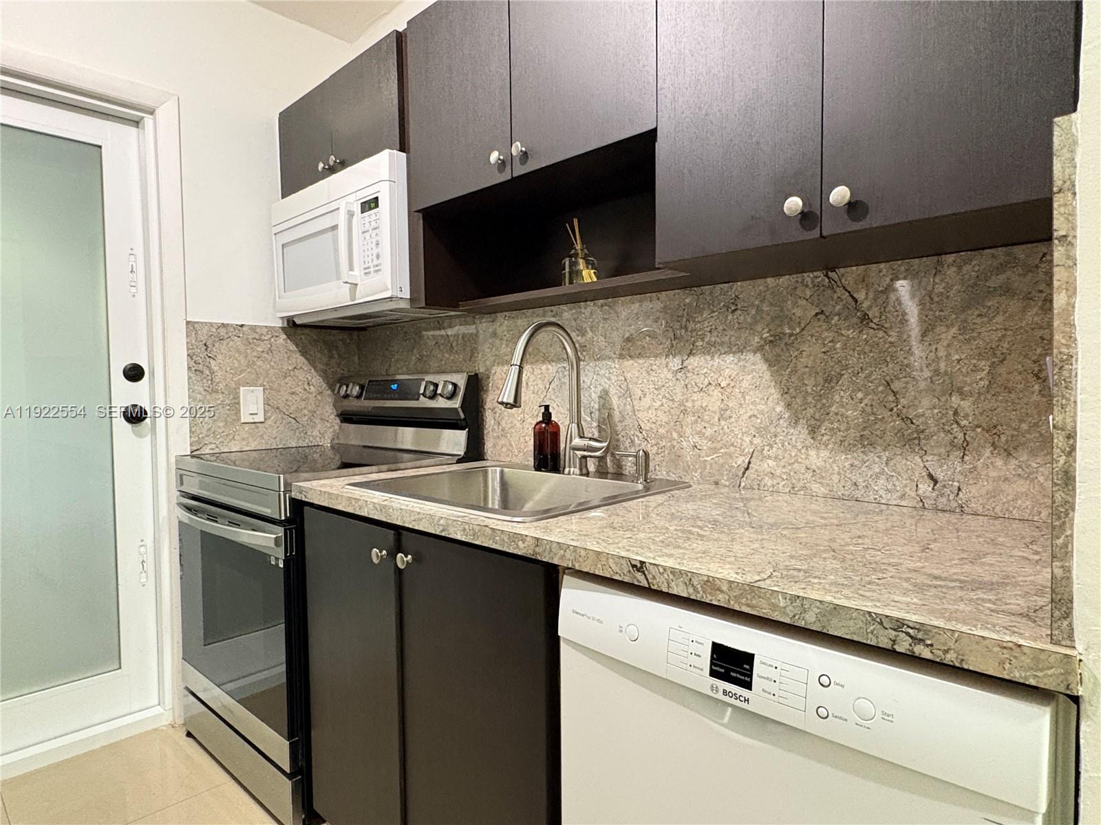 527 Southwest 9th Avenue, Unit 527 Miami, FL 33130 - Photo 11 of 34 a kitchen with granite countertop a sink and a stove top oven