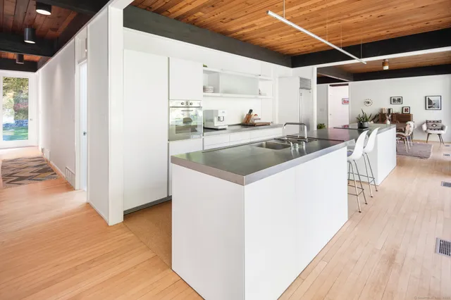 a view of a kitchen with a sink and dishwasher with wooden floor