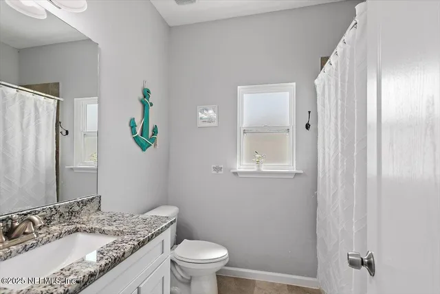 a bathroom with a granite countertop sink a toilet and a mirror