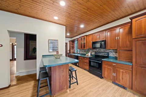 a kitchen with stainless steel appliances kitchen island granite countertop a stove top oven a sink dishwasher a dining table and chairs with wooden floor