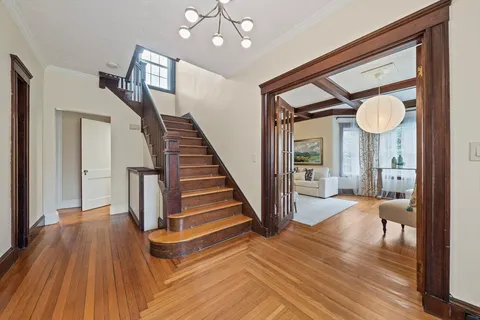 a view of a hallway with wooden floor and staircase
