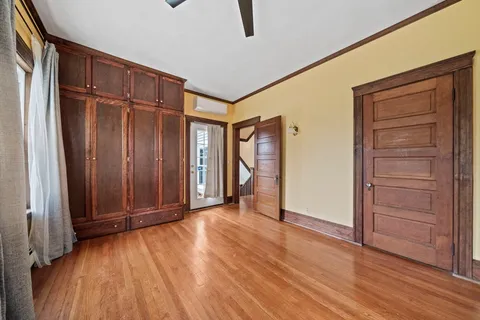 an empty room with wooden floor closet and windows