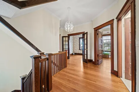 a view of a hallway with wooden floor and stairs