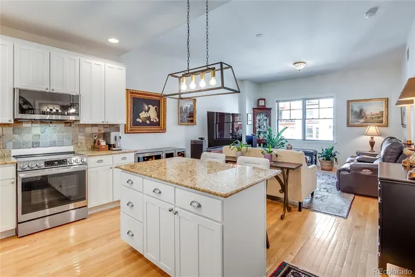 a kitchen with stainless steel appliances granite countertop a table chairs sink and cabinets
