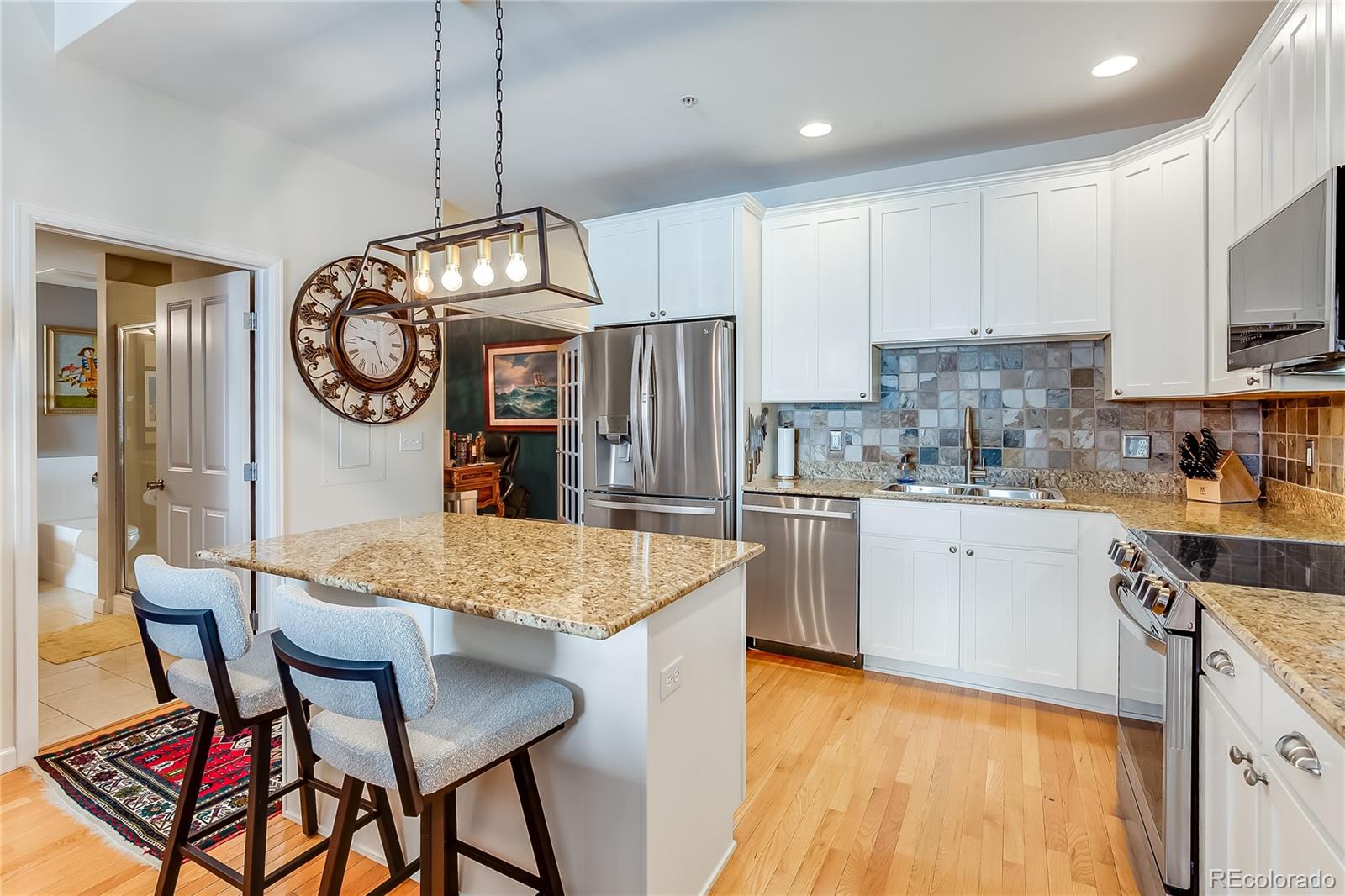 1950 Logan Street, Unit 814 Denver, CO 80203 - Photo 13 of 16 a kitchen with stainless steel appliances granite countertop a table chairs sink and cabinets
