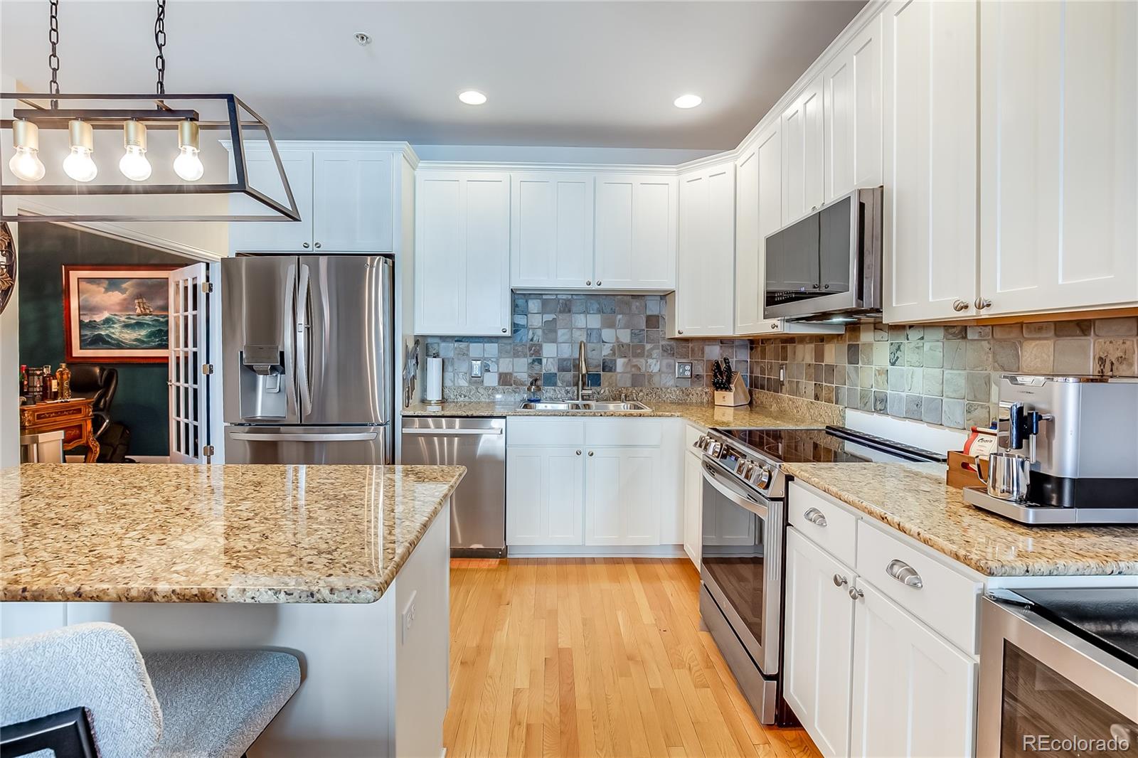 1950 Logan Street, Unit 814 Denver, CO 80203 - Photo 15 of 16 a kitchen with kitchen island granite countertop a stove top oven a sink a counter space and cabinets