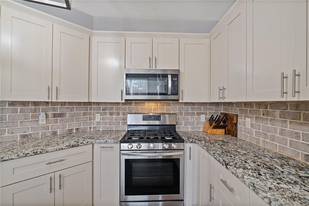 232 Springs Crossing Canton, GA 30114 - Photo 23 of 57 a kitchen with granite countertop white cabinets and stainless steel appliances
