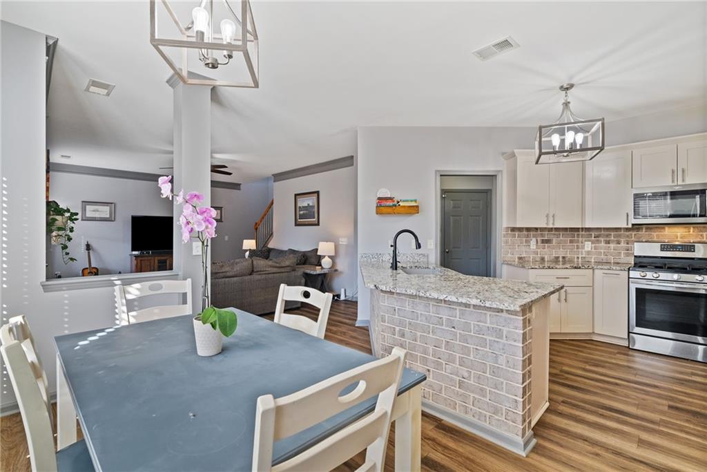 232 Springs Crossing Canton, GA 30114 - Photo 26 of 57 a kitchen with granite countertop kitchen island stainless steel appliances a sink dishwasher a stove a dining table and chairs with wooden floor
