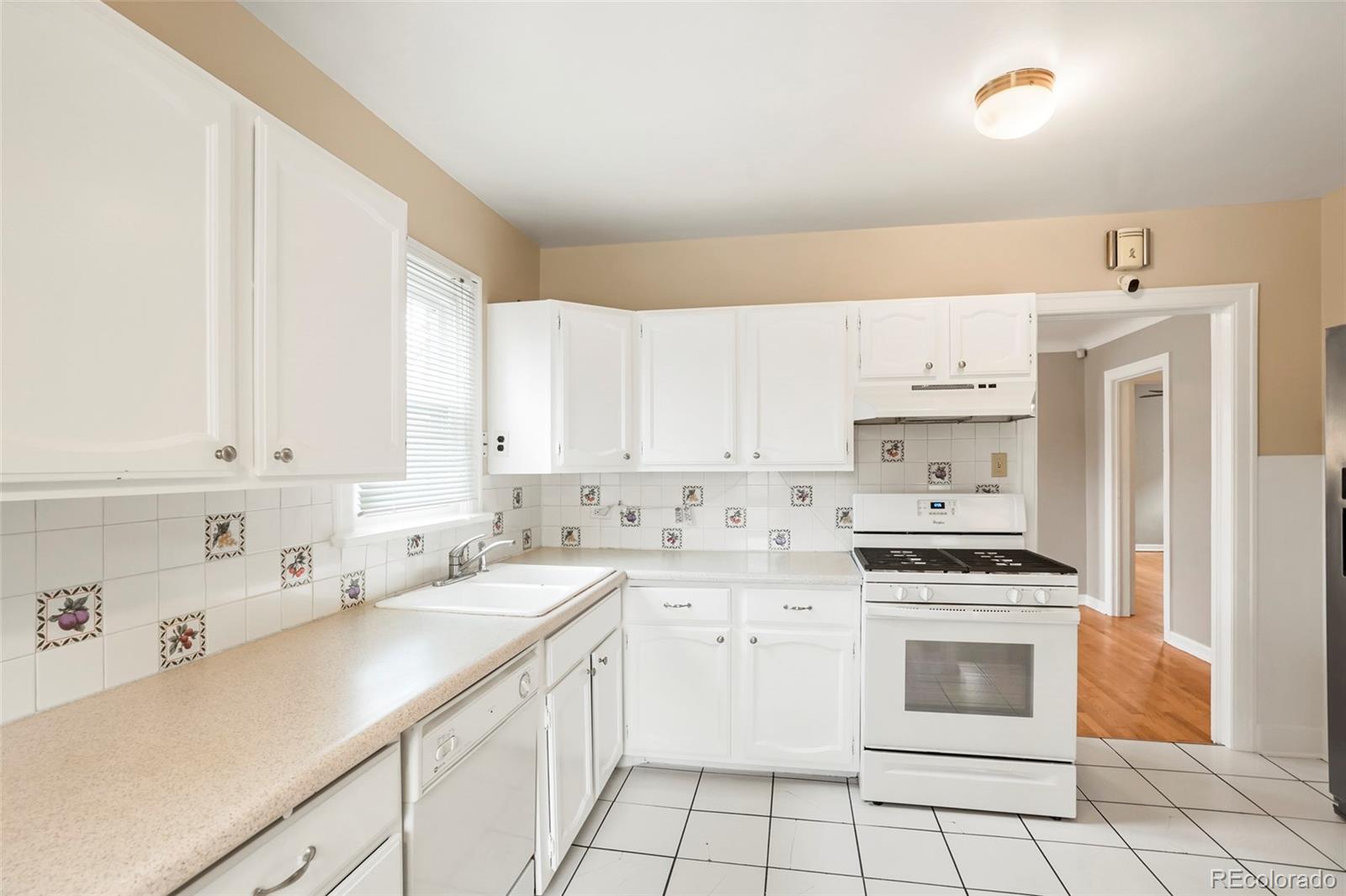 1175 Cook Street Denver, CO 80206 - Photo 11 of 42 a kitchen with white cabinets and white appliances
