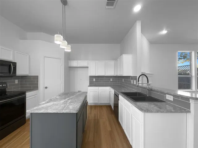 a kitchen with kitchen island granite countertop a sink a counter space appliances and cabinets