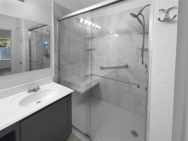 a bathroom with a shower sink vanity and mirror
