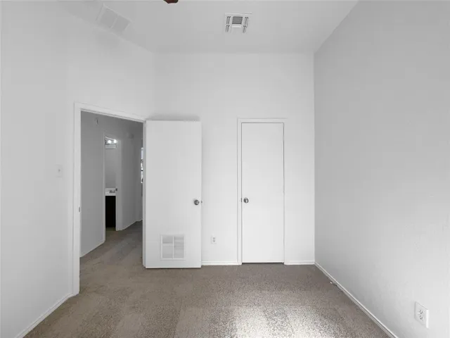 a view of an empty room with closet and a bathroom
